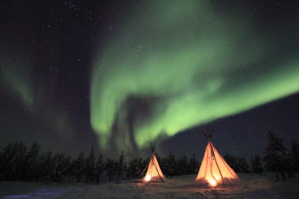 Aurora borealis dances above a tee pee in Canada.